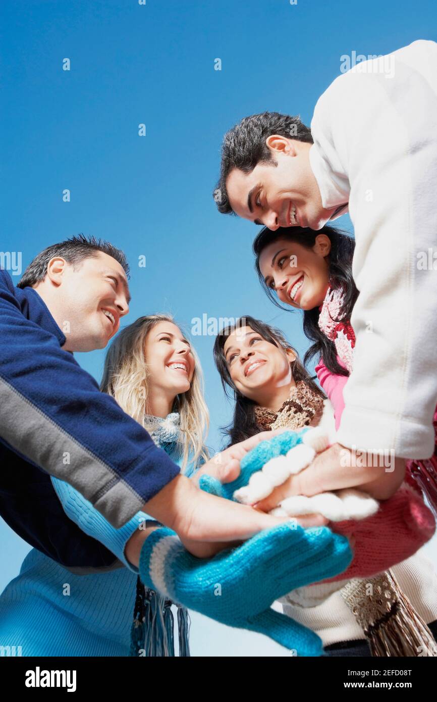 Low-Angle-Ansicht von zwei jungen Frauen und zwei Mitte Erwachsene Männer mit einer mittleren erwachsenen Frau, die Hände stapelt Stockfoto
