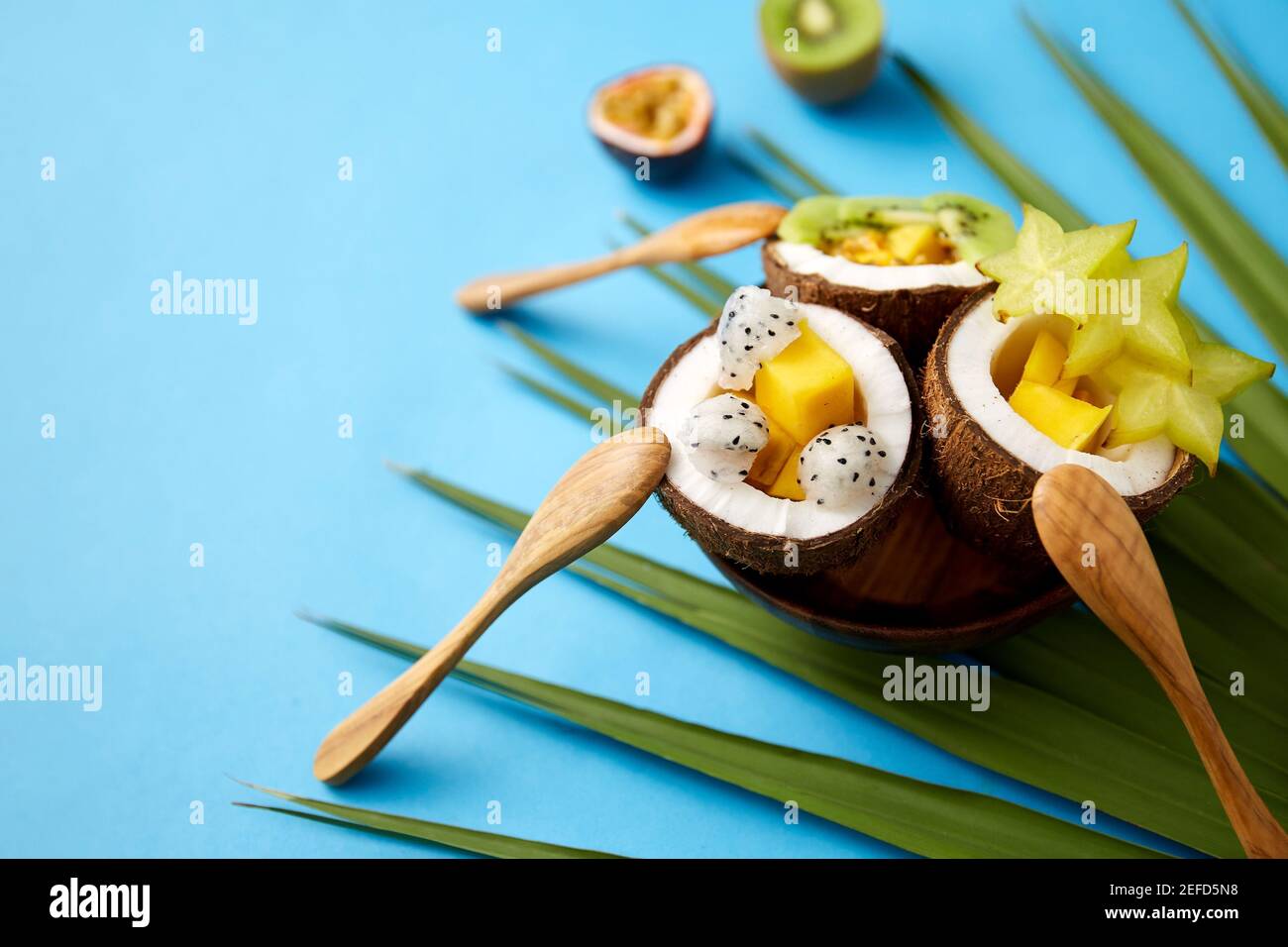 Mischung aus exotischen Früchten in Kokosnussschalen mit Löffeln Stockfoto