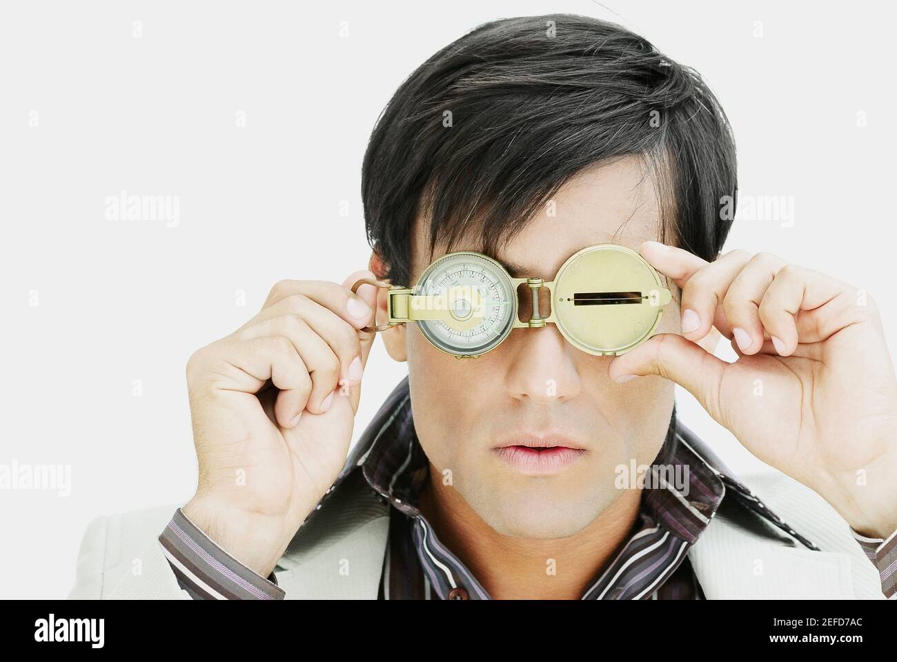 Nahaufnahme eines jungen Mannes, der durch einen Kompass schaut Stockfoto