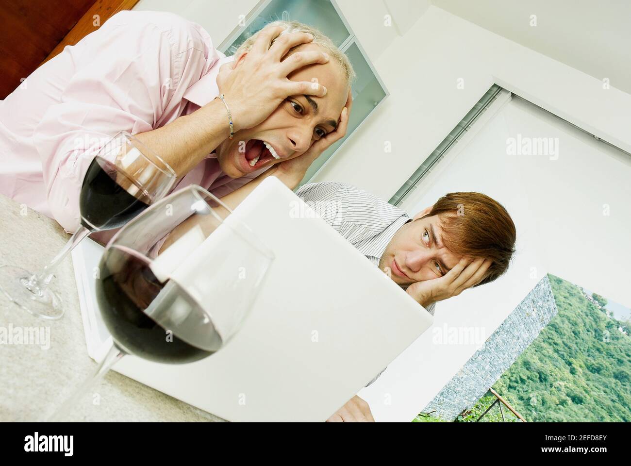 Nahaufnahme eines jungen Mannes, der mit einem schockierten jungen Mann sitzt Stockfoto