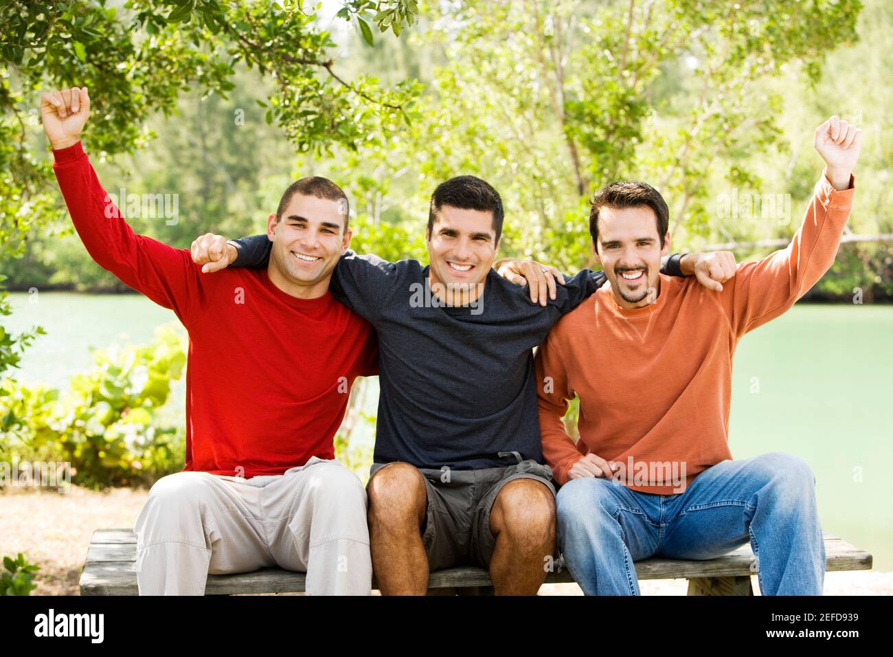 Porträt eines mittleren erwachsenen Mannes und zweier junger Männer Sitzen auf einer Bank Stockfoto