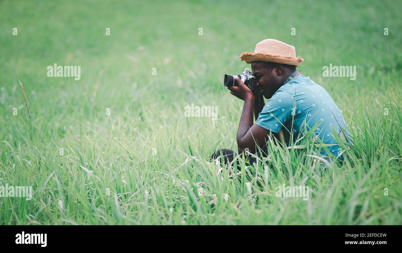 Afrikanischer Mann Reisende fotografieren zwischen grünen Wiesen field,16:9 Stil Stockfoto