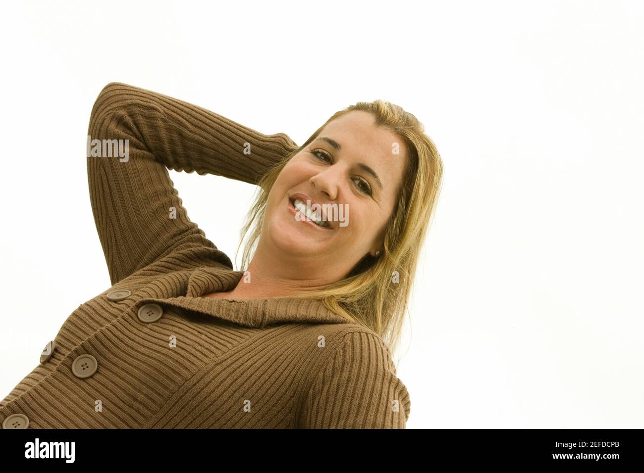 Porträt einer mittleren erwachsenen Frau, die mit ihrer Hand lächelt In ihren Haaren Stockfoto