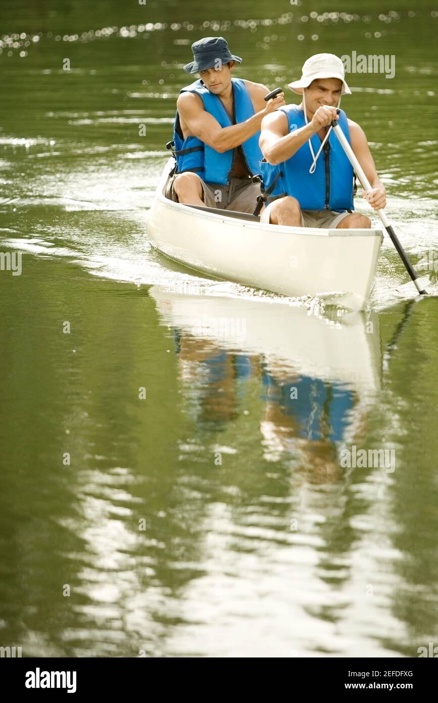Zwei Männer mit mittlerem Erwachsenenalter, die in einem See Boot fahren Stockfoto