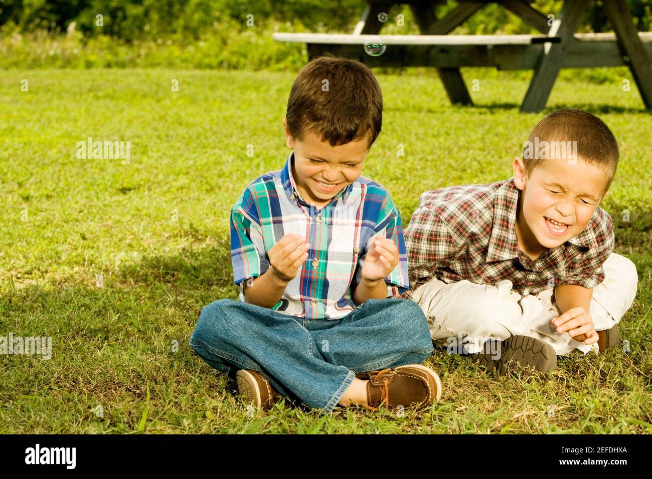 Nahaufnahme von zwei Jungen, die lächelnd im Garten sitzen Stockfoto