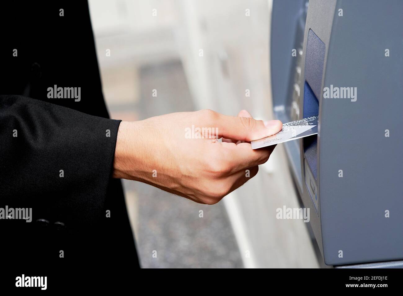 Nahaufnahme einer personÅ½s Hand, in die eine Kreditkarte eingelegt wird Ein Geldautomat Stockfoto
