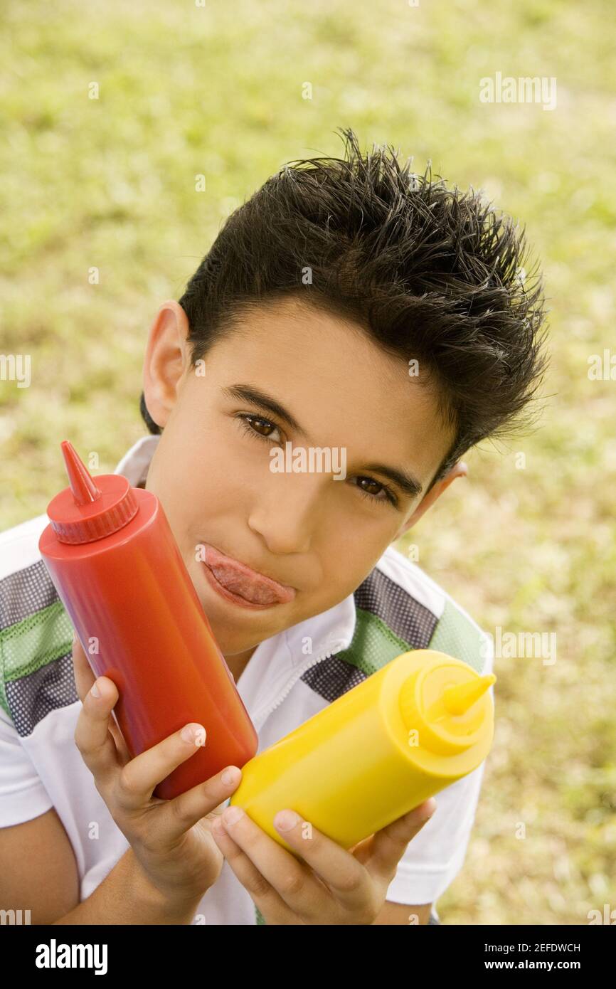 Porträt eines Jungen mit Ketchup und Senfflasche Stockfoto