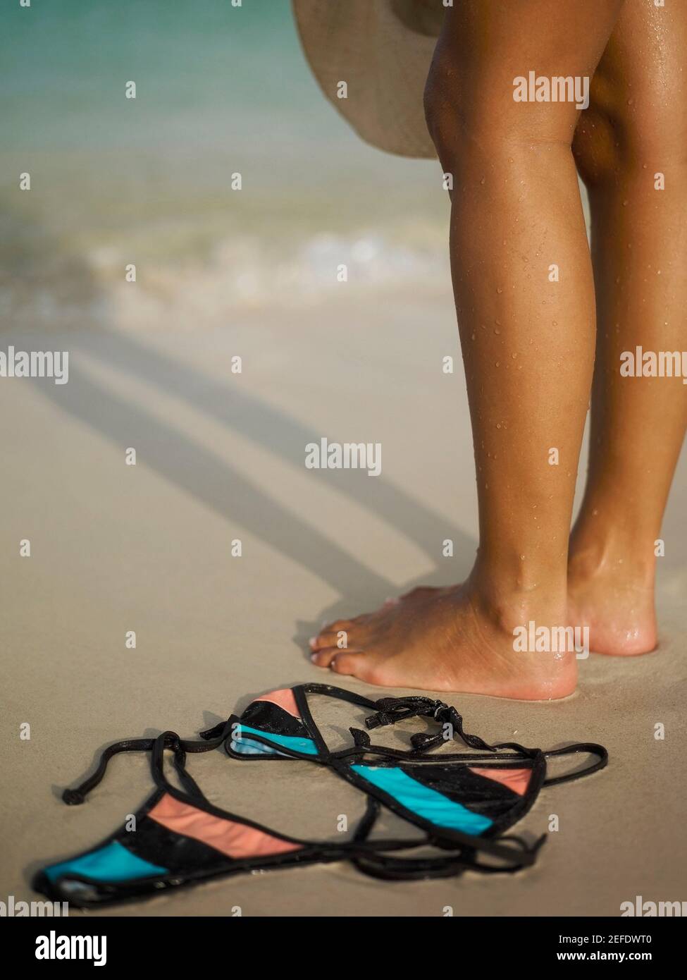 Niedrige Ansicht einer Frau, die am Strand steht In der Nähe eines Bikinis Stockfoto