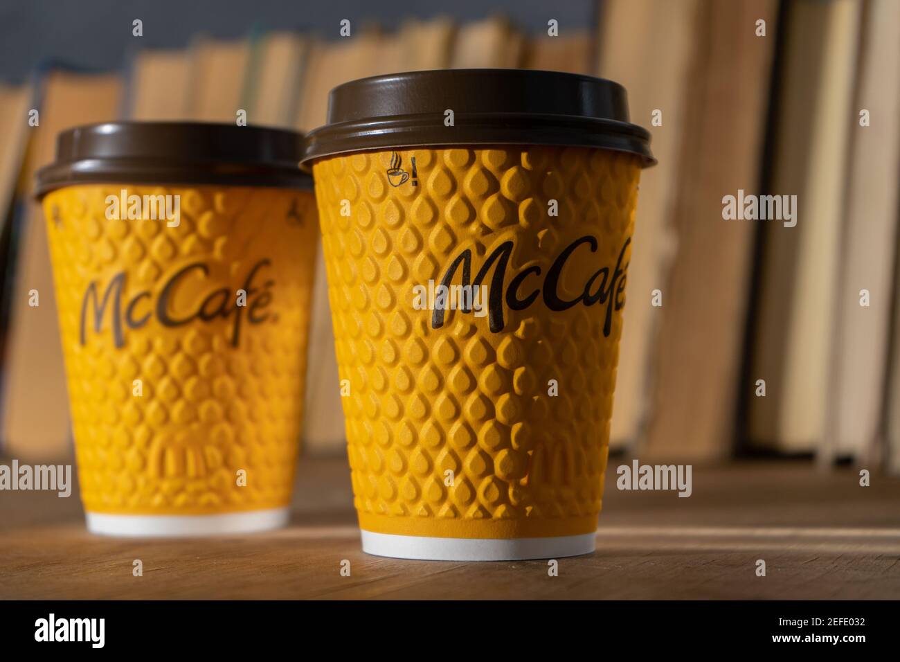 Ukraine, Kiew - 17. Februar 2021: Gelbes Glas Kaffee von McDonald's. Papierglas Drink McCafe. Kaffeetasse auf Tisch mit Schatten. Menü in Fastfood Stockfoto