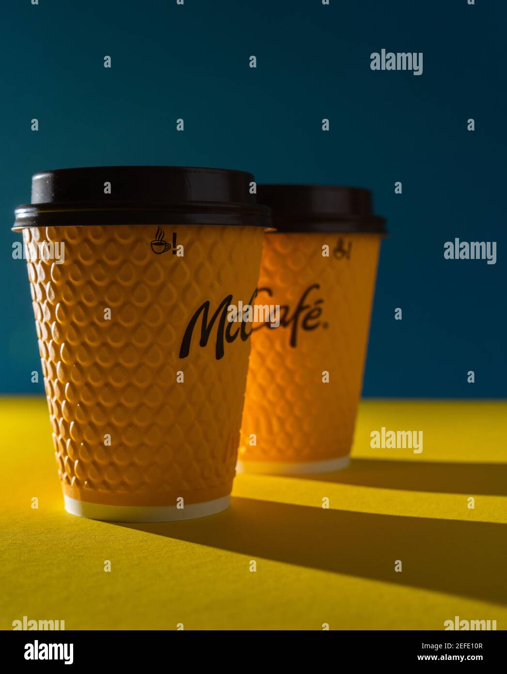 Ukraine, Kiew - 17. Februar 2021: Gelbes Glas Kaffee von McDonald's. Papierglas Drink McCafe. Kaffeetasse auf Tisch mit Schatten. Menü in Fastfood Stockfoto