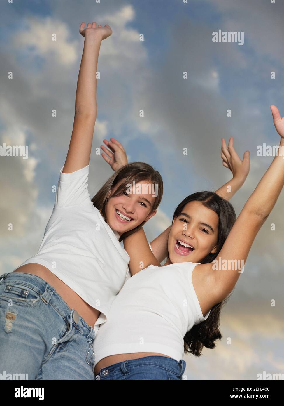 Low-Angle-Ansicht eines Teenagers und ihrer Schwester Stehend mit ausgestreckten Armen Stockfoto