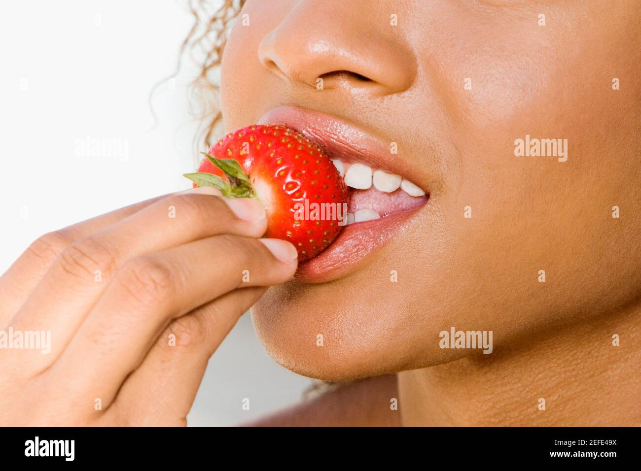 Nahaufnahme einer jungen Frau eine Erdbeere essen Stockfoto