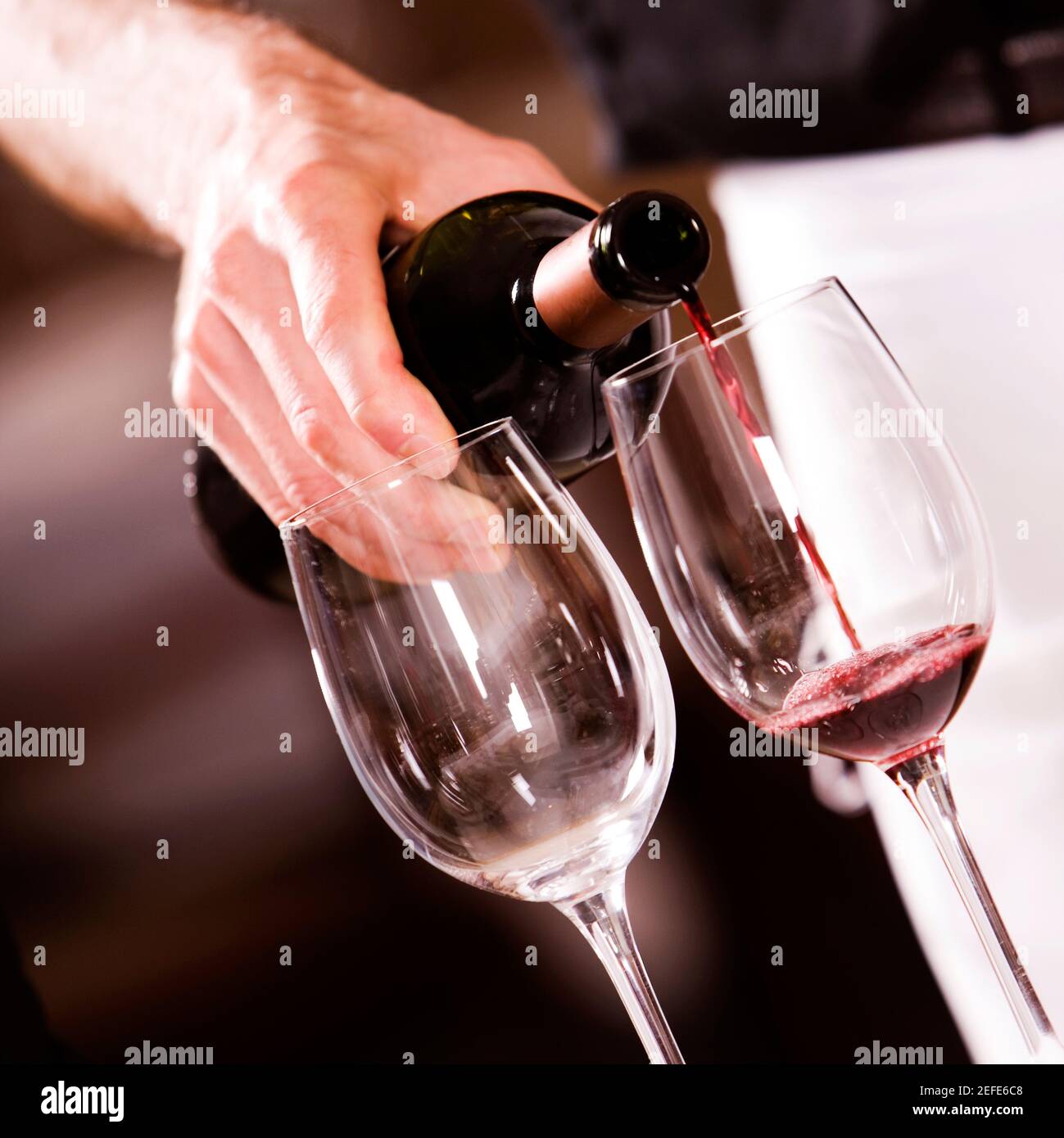 Mittlere Ansicht eines Mannes, der Rotwein hineingießt Ein Weinglas Stockfoto