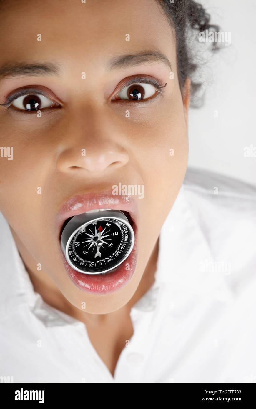 Porträt einer Geschäftsfrau, die einen Kompass im Mund hält Stockfoto