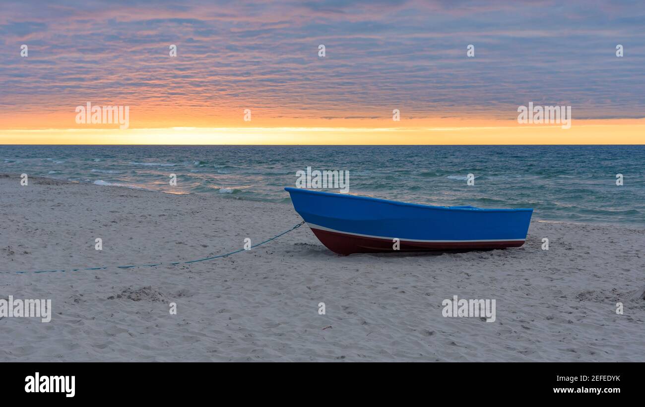 Blaues Boot am Strand an der Ostsee bei Sonnenuntergang Stockfoto