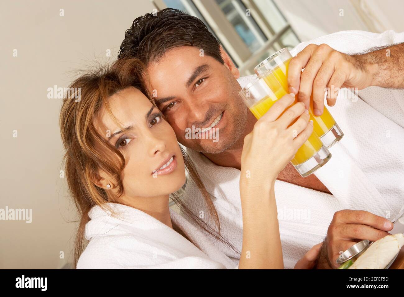 Porträt eines mittleren Erwachsenen Paar toasten mit Gläsern von Saft Stockfoto