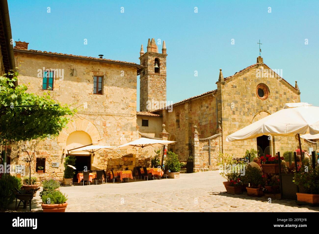 Straßencafé vor einer Kirche, romanische Kirche, Piazza Roma, Monteriggioni, Provinz Siena, Toskana, Italien Stockfoto
