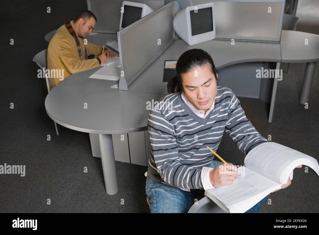 Zwei junge Männer sitzen in einem Computerlabor und schreiben Stockfoto