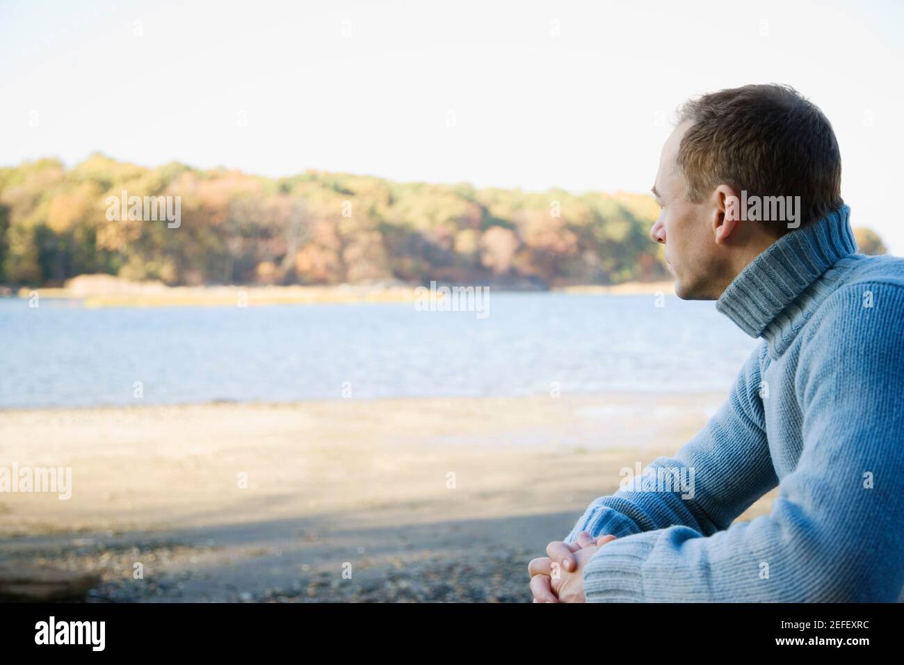 Seitenprofil eines mittelerwachsenen Mannes, der mit ihm sitzt Hände zusammengeklemmt Stockfoto