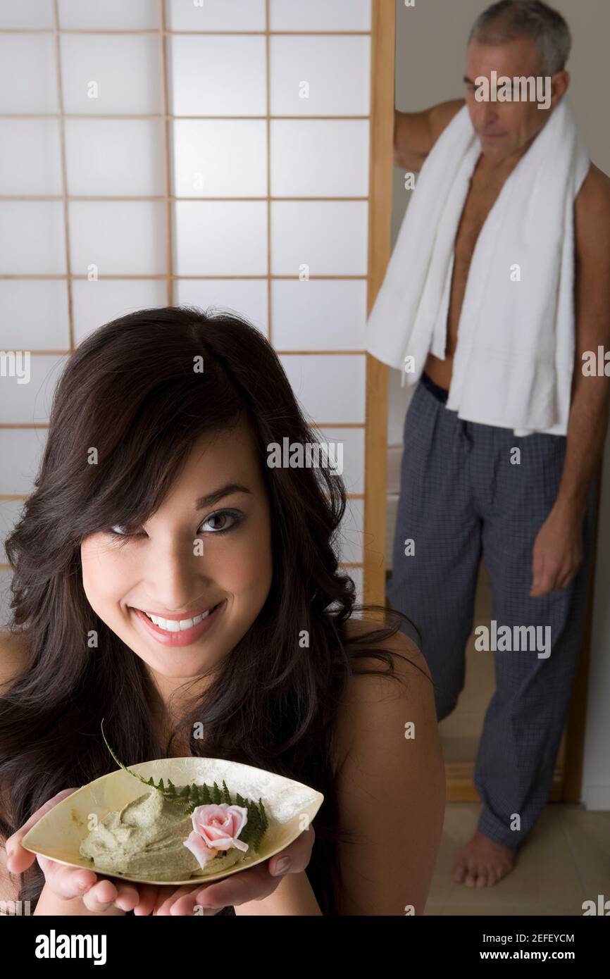 Nahaufnahme einer jungen Frau, die eine Schüssel mit Kraut in der Hand hält Mit ihrem Vater, der hinter ihr steht Stockfoto