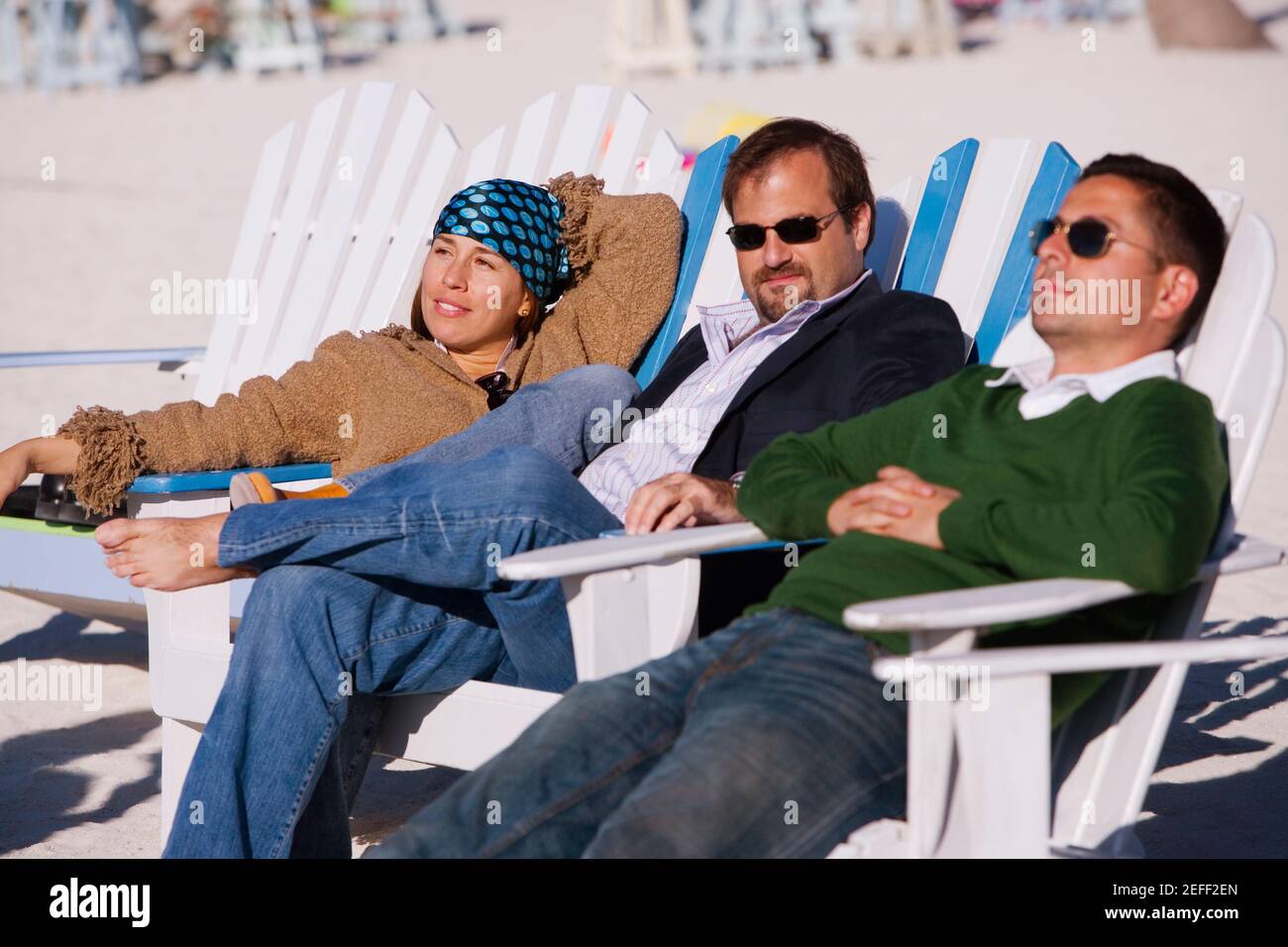 Zwei Männer mittleren Erwachsenen mit einer Frau mittleren Erwachsenen liegend Auf Liegestühlen Stockfoto