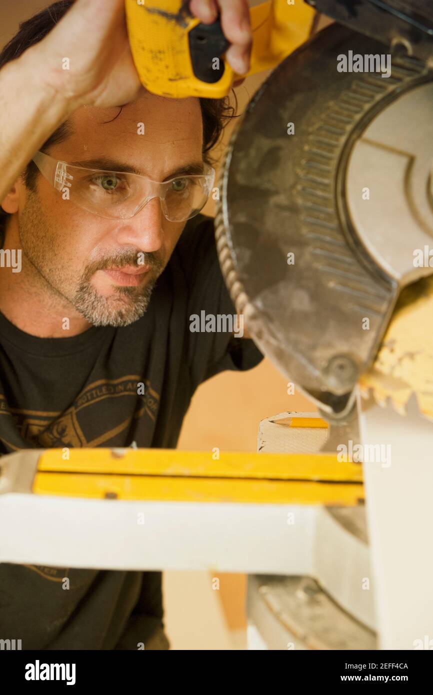 Nahaufnahme eines mittleren Erwachsenen, der eine Kreissäge betreibt Stockfoto