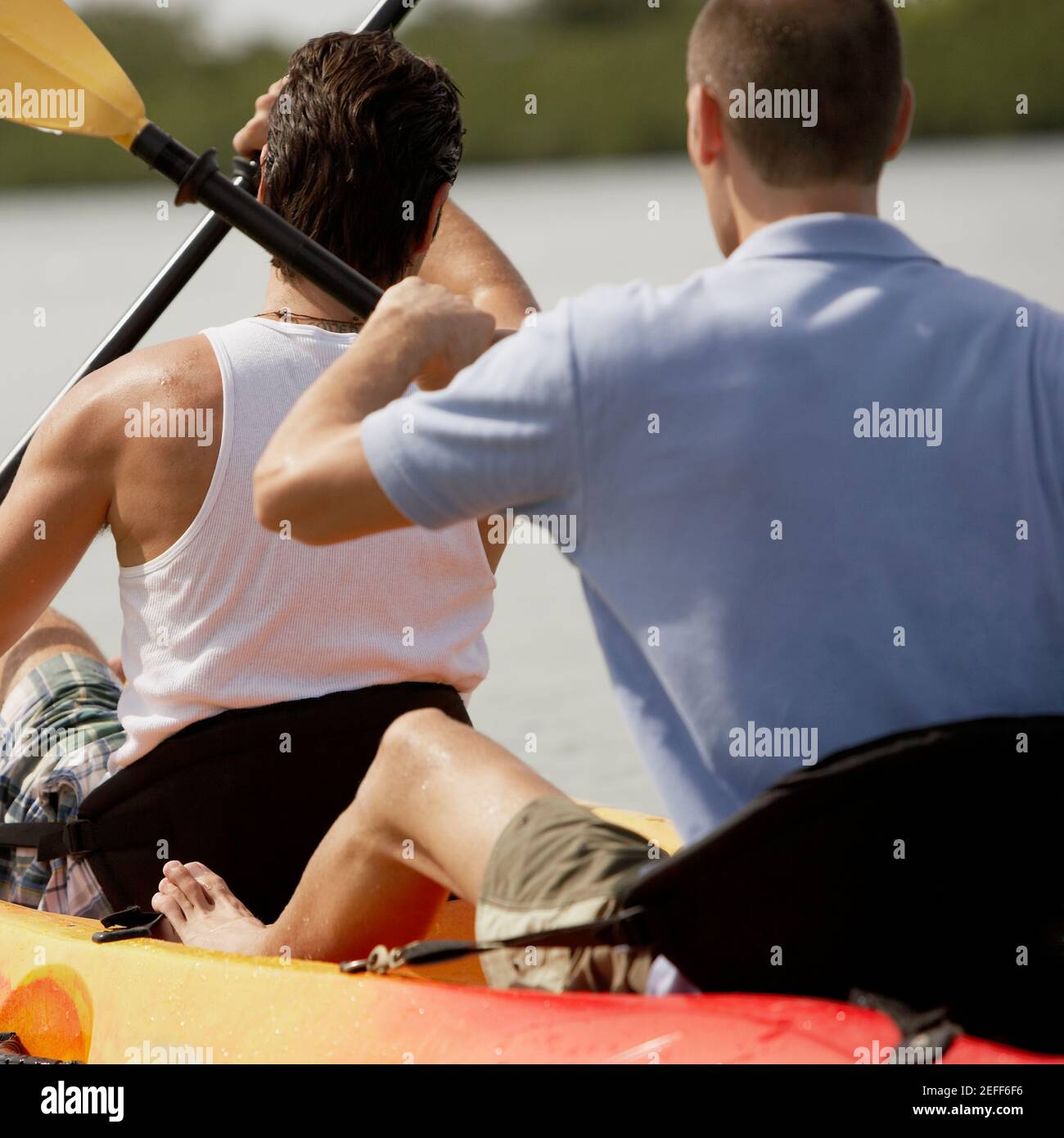 Rückansicht von zwei jungen Männern beim Kajakfahren Stockfoto