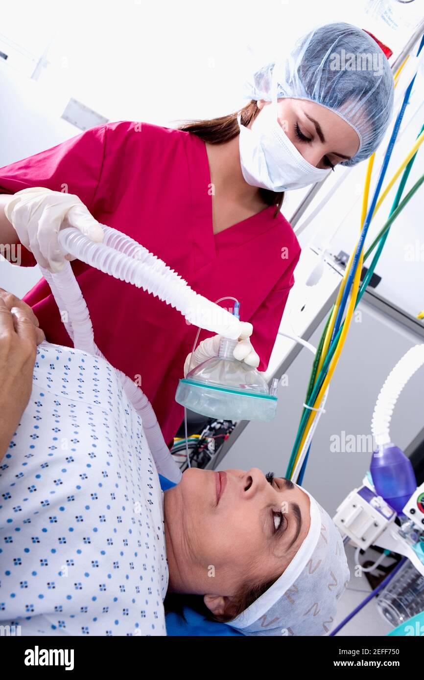 Weibliche Chirurgen setzen eine Sauerstoffmaske auf eine weibliche patientÅ½s Gesicht Stockfoto