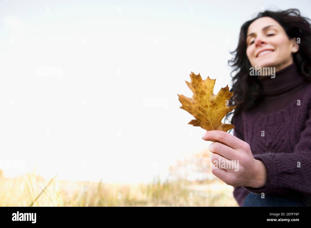 Nahaufnahme einer reifen Frau mit Ahornblatt und Lächelnd Stockfoto