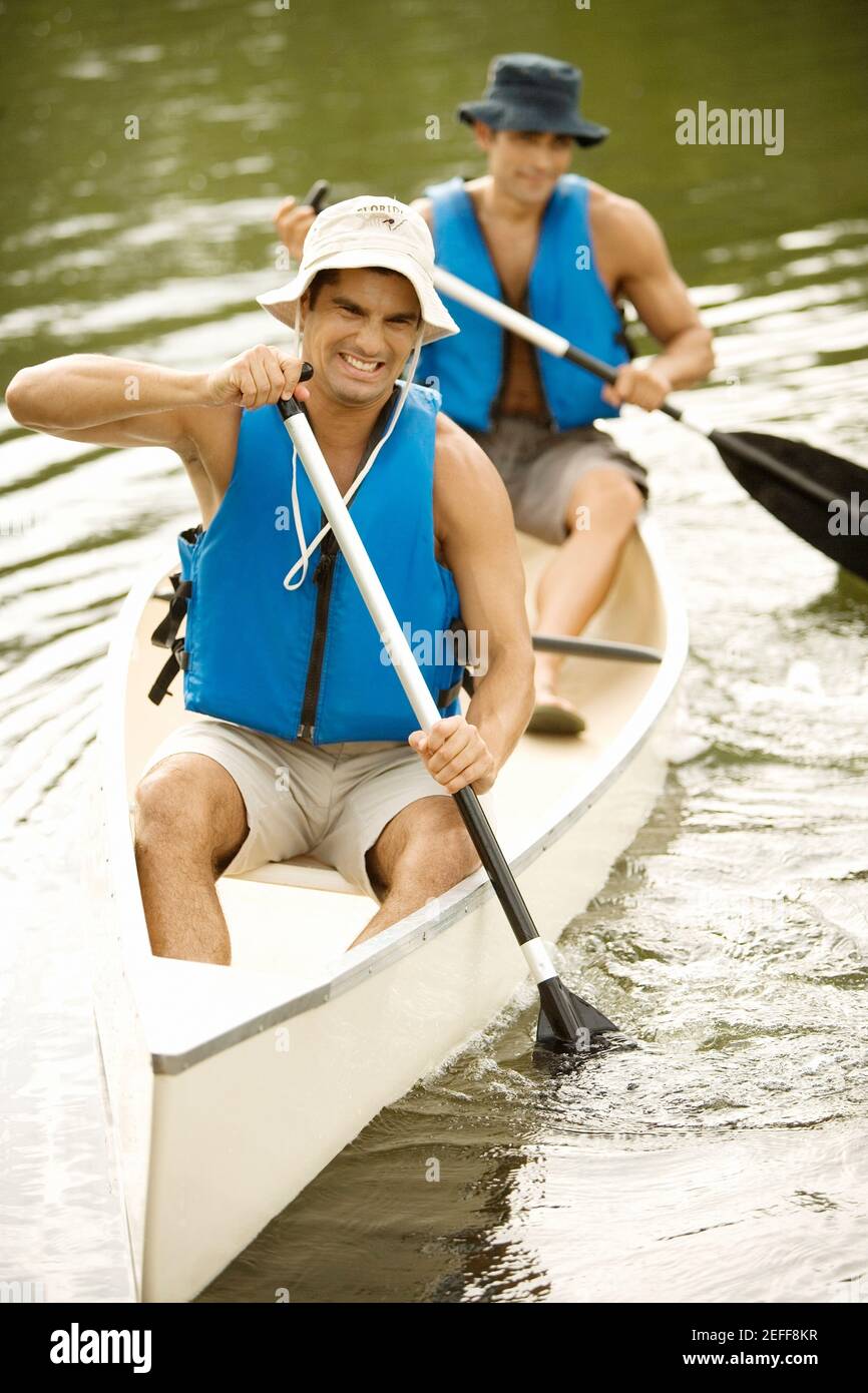 Zwei Männer mit mittlerem Erwachsenenalter, die in einem Fluss Boot fahren Stockfoto