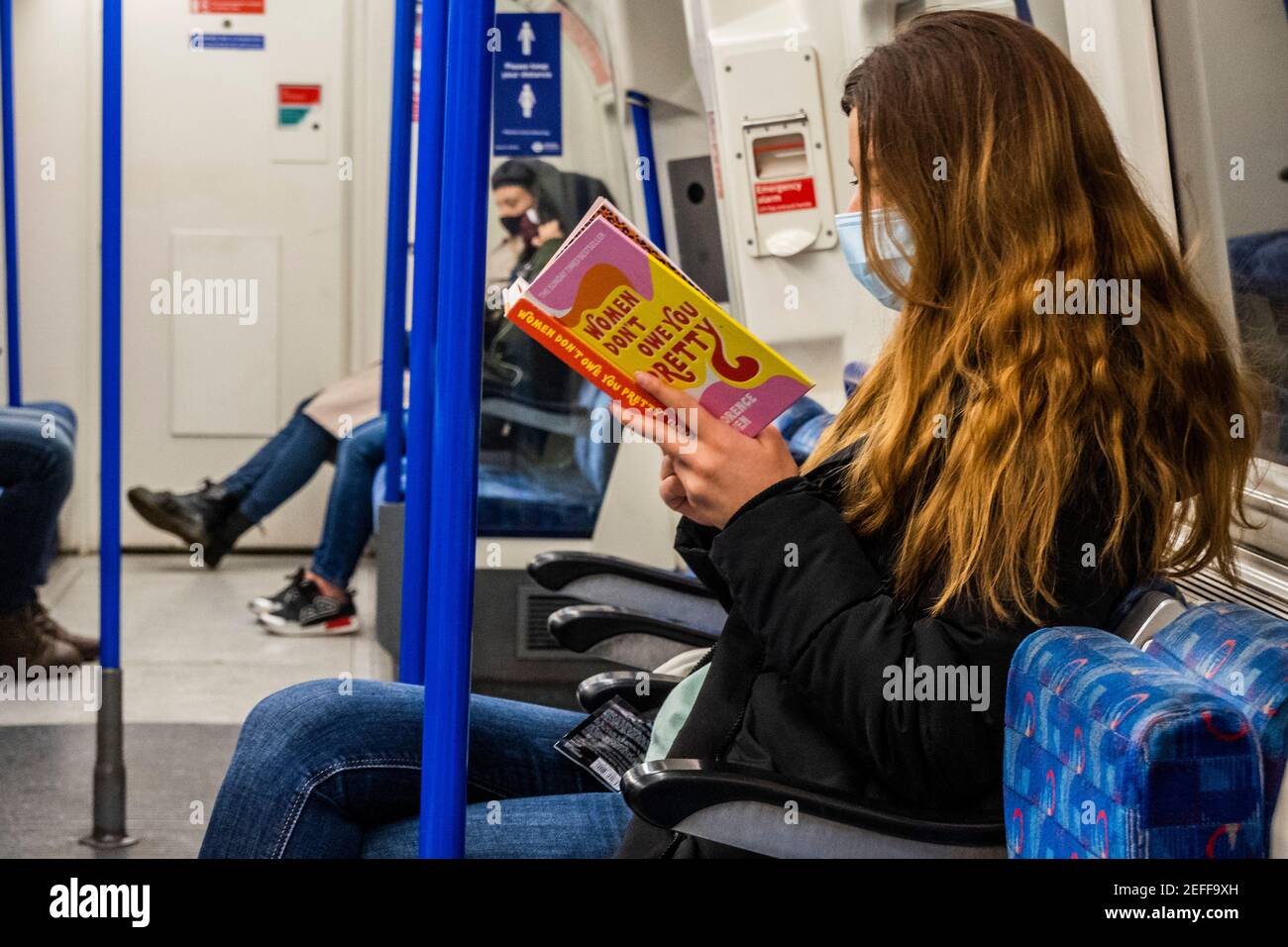 London, Großbritannien. Februar 2021, 17th. Eine Frau liest Women Don't Owe You Pretty: Das Debüt-Buch aus Florenz gegeben - der Untergrund ist manchmal ruhig während der nationalen Lockdown, Stay At Home, Anweisungen. Die meisten Reisenden tragen Masken, da sie bereits obligatorisch sind. Kredit: Guy Bell/Alamy Live Nachrichten Stockfoto