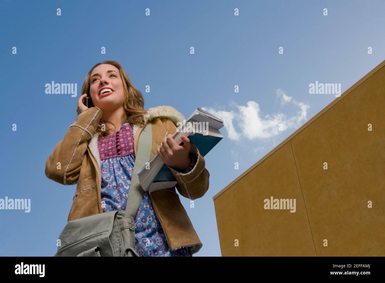 Low-Winkel-Ansicht einer jungen Frau hält Bücher und Sprechen auf einem Mobiltelefon Stockfoto