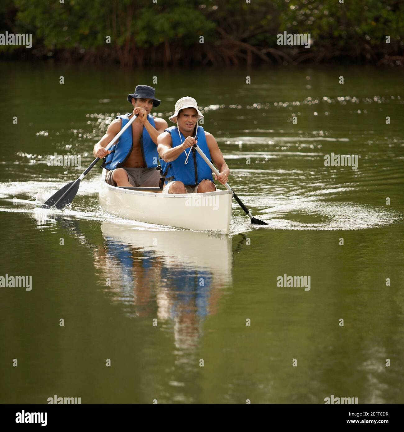 Zwei Männer mit mittlerem Erwachsenenalter, die Kanu fahren Stockfoto