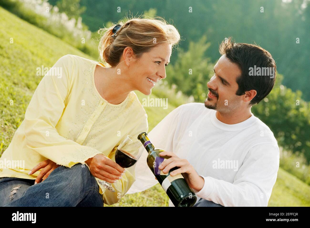 Nahaufnahme eines reifen Mannes, der Wein in einen jungen Mann gießt womanÅ½s-Glas Stockfoto