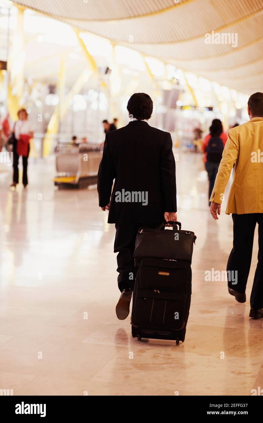 Rückansicht eines Mannes, der an einem Flughafen, Madrid, Spanien, läuft und Gepäck zieht Stockfoto