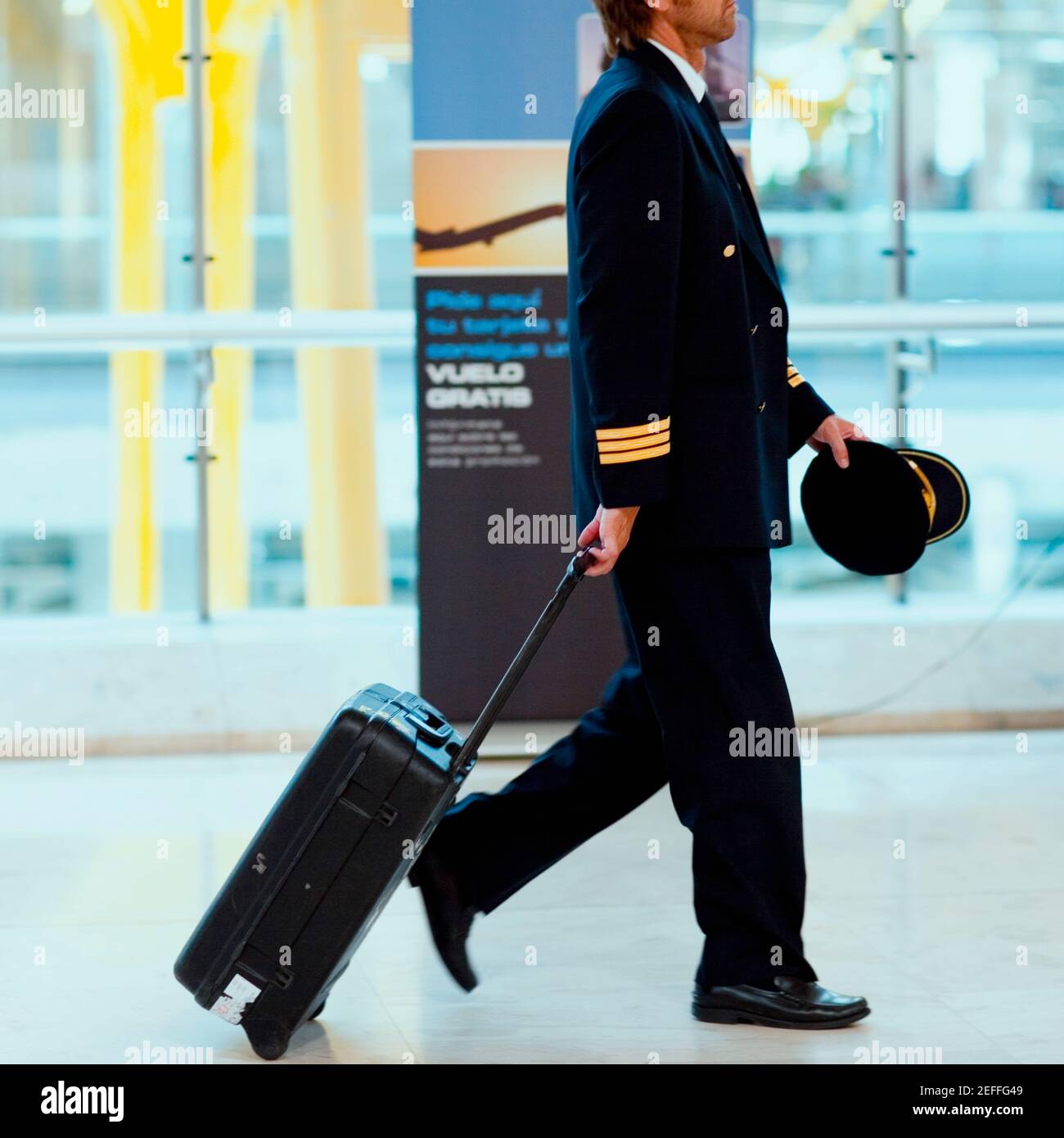 Seitenprofil eines Piloten, der das Gepäck auf einem Flughafen, Madrid, Spanien zieht Stockfoto