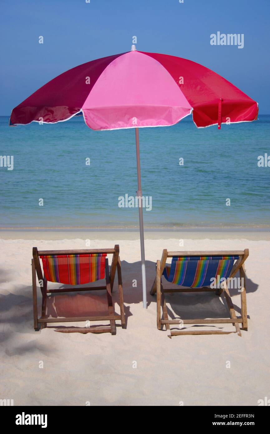 Zwei Liegestühle unter einem Sonnenschirm am Strand, Phi Phi Inseln, Thailand Stockfoto