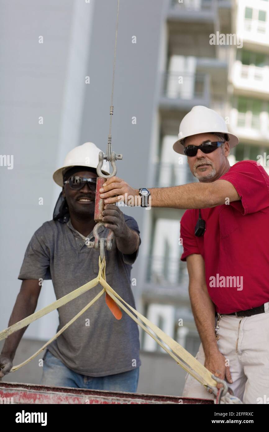 Zwei männliche Bauarbeiter, die auf einer Baustelle arbeiten Stockfoto