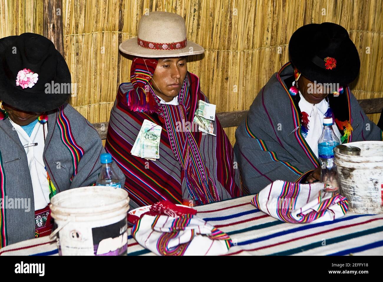 Zwei reife Männer sitzen mit einem Bräutigam an einem Tisch, Taquile Island, Titicacasee, Puno, Peru Stockfoto