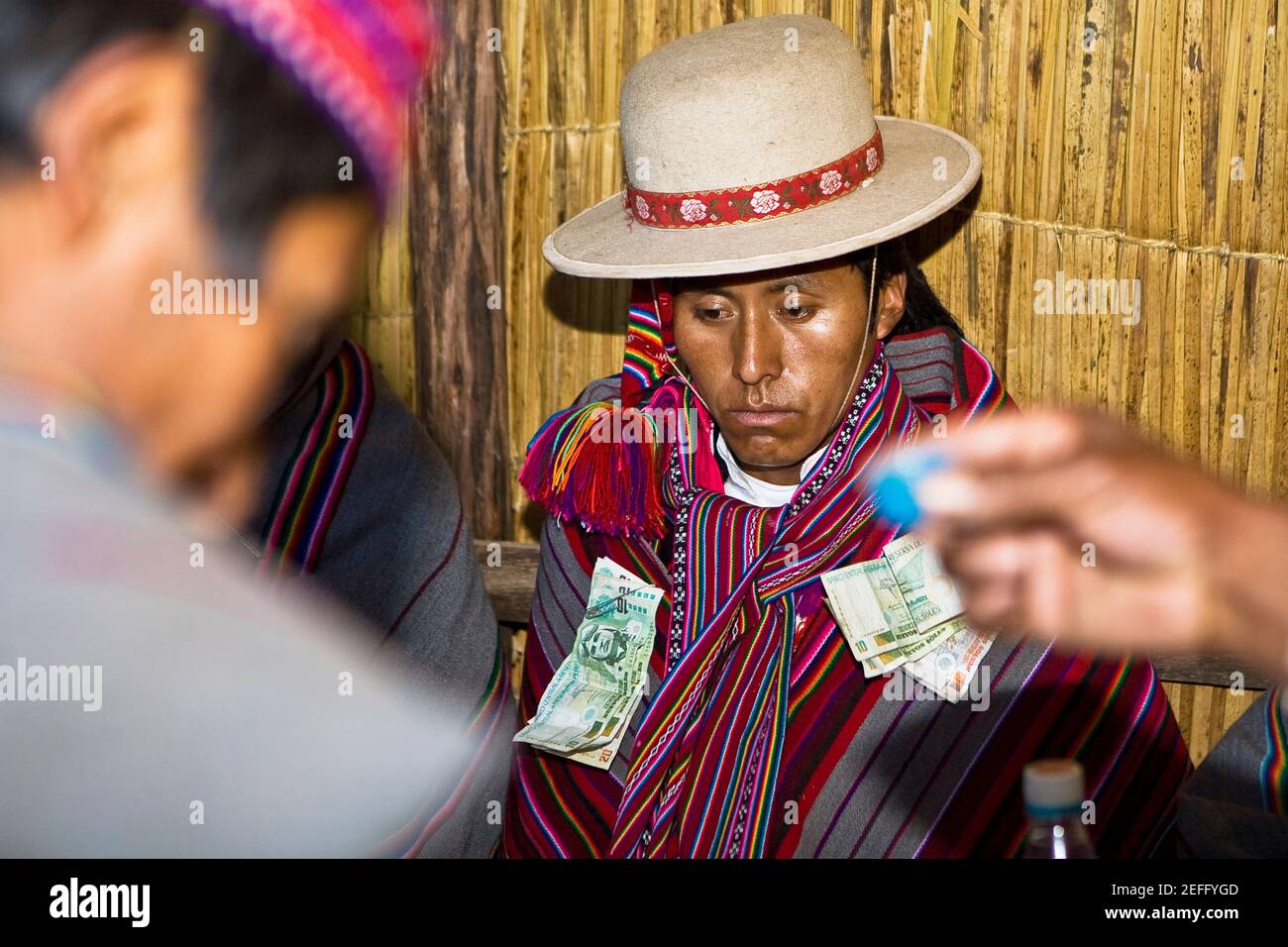 Nahaufnahme eines jungen Mannes, der bei einer Hochzeitszeremonie auf der Insel Taquile, dem Titicacasee, Puno, Peru, sitzt Stockfoto