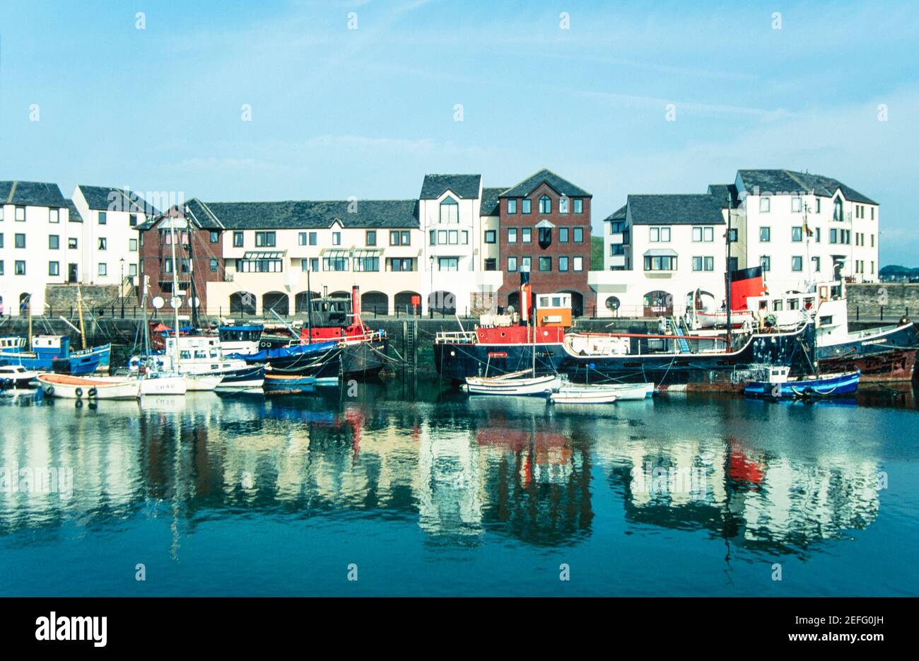 1992 Maryport Cumbria - das Elizabeth Dock bildet das Herz des funktionierenden Hafens von Maryport und ist die Heimat der Fischereiflotte, wenn sie sich im Hafen befindet. Das Elizabeth Dock, benannt nach Elizabeth Senhouse, wurde am 20th. Oktober 1857 eröffnet.die Familie Senhouse war Grundbesitzer in der Gegend und verantwortlich für die Entwicklung der Stadt und Ausgrabungen ihrer römischen Vergangenheit.Humphrey Senhouse nannte die neue Stadt nach seiner Frau Mary. Elizabeth Dock ist Teil des Flusses Ellen Flow.Fischerboote in der Sicherheit von Elizabeth Dock und moderne Apartments in der Cumbrian Stadt Maryport Cumbria England GB UK Europa Stockfoto