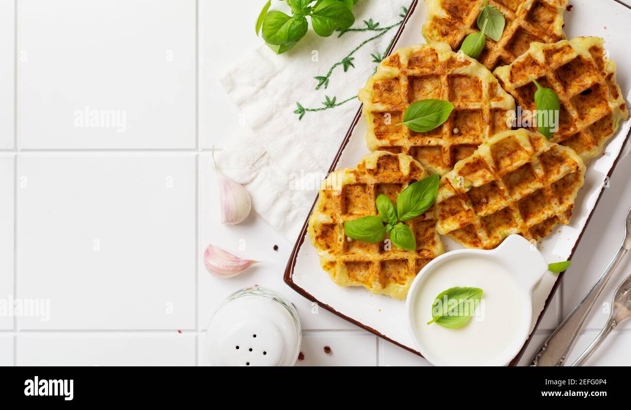 Hausgemachte Zucchini Waffeln mit Käse, Sause und Blatt Basilikum auf weißem Hintergrund. Konzept der Keto Ernährung Lebensmittel. Selektiver Fokus. Stockfoto