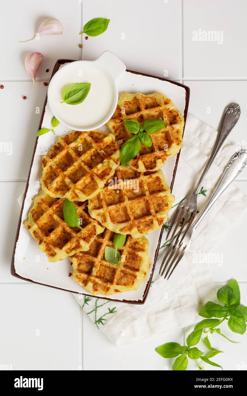 Hausgemachte Zucchini Waffeln mit Käse, Sause und Blatt Basilikum auf weißem Hintergrund. Konzept der Keto Ernährung Lebensmittel. Selektiver Fokus. Stockfoto