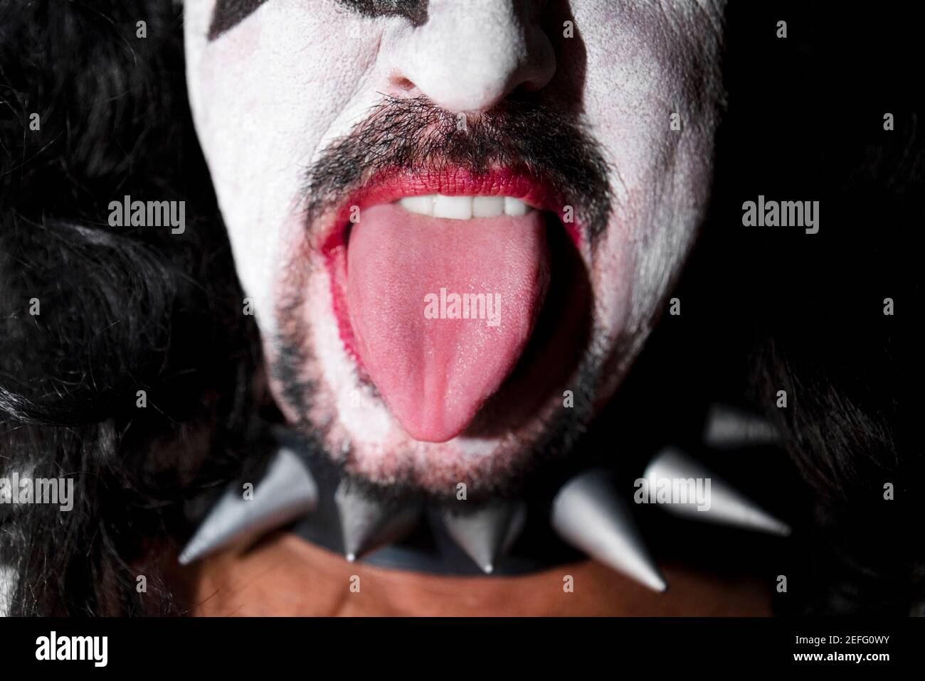 Nahaufnahme eines Mannes, der einen Stachelhals trägt und Zeigt seine Zunge Stockfoto