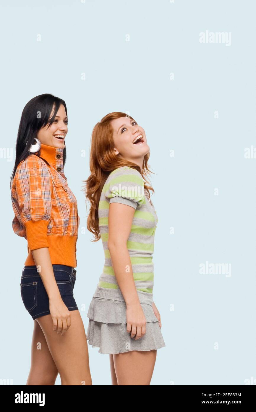 Seitenansicht zweier junger Frauen in einer Reihe stehen und lachen Stockfoto