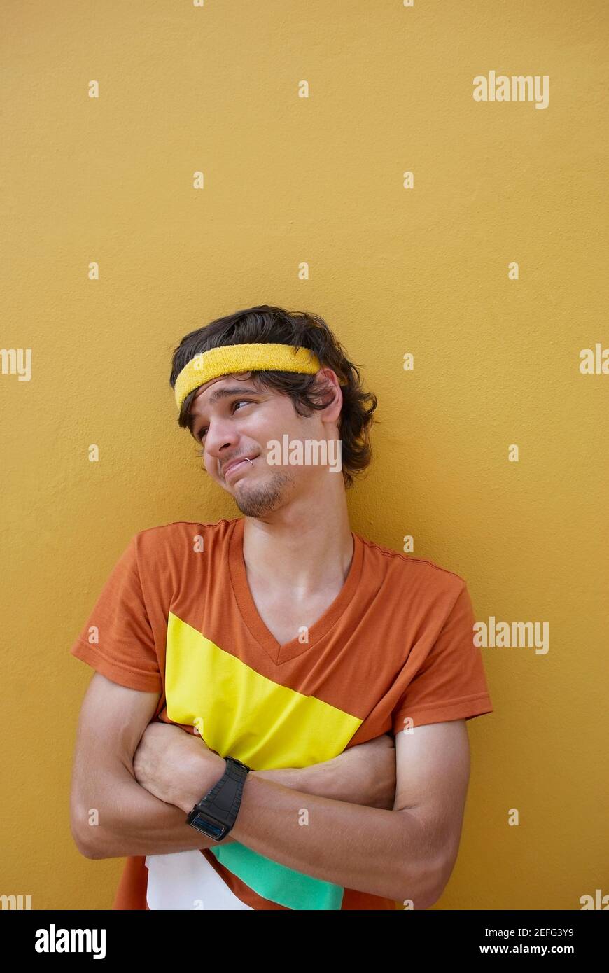 Junger Mann stehend mit seinem verschränkten Armen und Grimasse Stockfoto