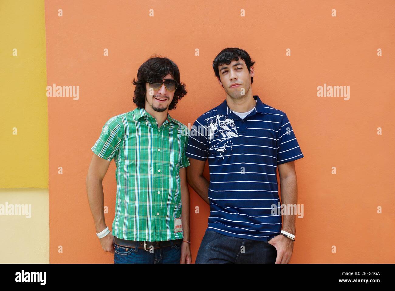 Zwei junge Männer vor einer Wand stehend Stockfoto