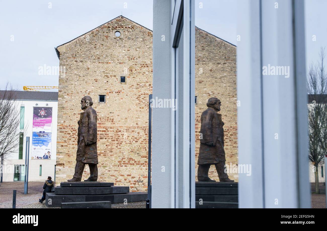 16. Februar 2021, Rheinland-Pfalz, Trier: Die Karl-Marx-Statue auf dem Simeonstiftplatz spiegelt sich in einem Fenster. Die Statue wurde am 5. Mai 2018 anlässlich des 200th. Jahrestages der Geburt von Karl Marx in seiner Heimatstadt enthüllt. Der Philosoph, Ökonom, Journalist und Autor des "Kapitals", der Kritik der kapitalistischen Gesellschaft des 19th. Jahrhunderts, wurde am 5. Mai 1818 in Trier geboren. Foto: Andreas Arnold/dpa Stockfoto