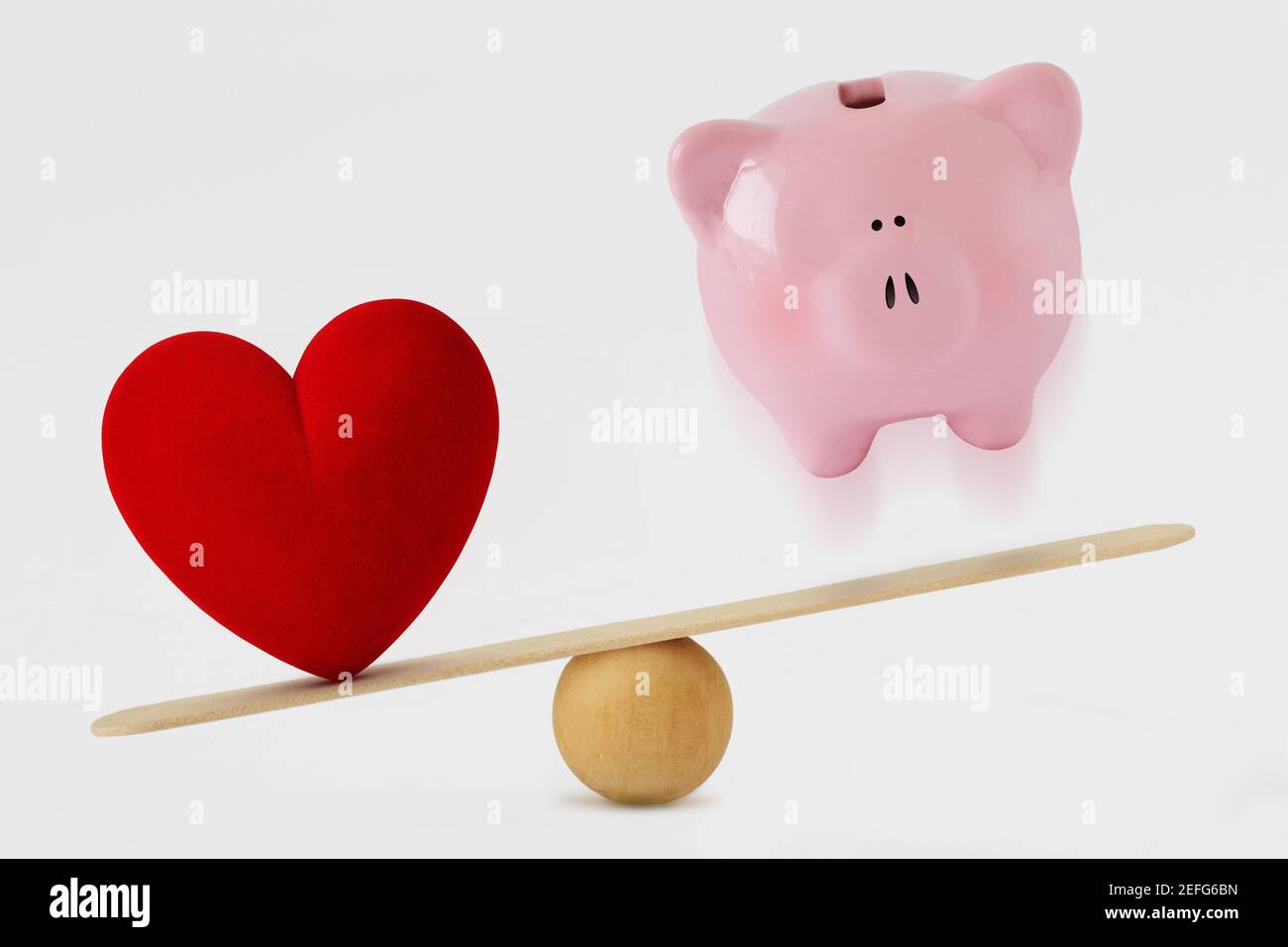 Herz und Sparschwein auf Waage - Konzept der Liebe Priorität im Leben Stockfoto
