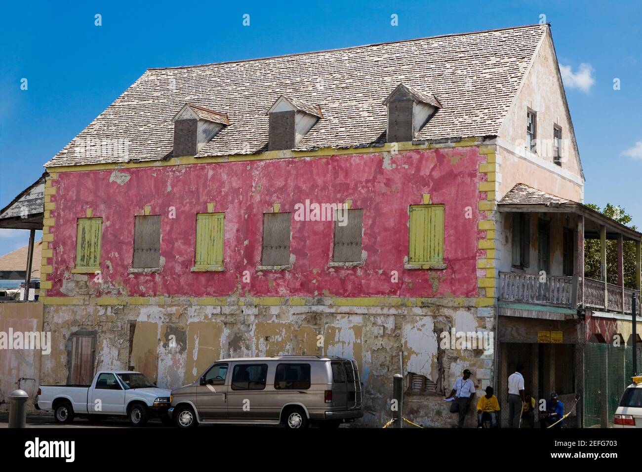 Zwei Fahrzeuge geparkt neben einem Haus, Bay Street, Nassau, Bahamas Stockfoto